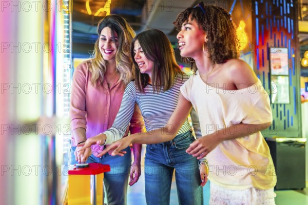 Three female friends enjoying a vibrant summer night out in the city, laughing and playing arcade games together, creating joyful memories