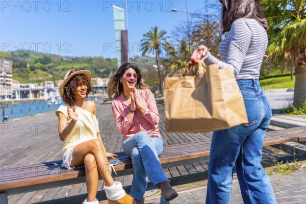 Three happy women enjoying sunny day in a city with palm trees and waterfront view, having fun together