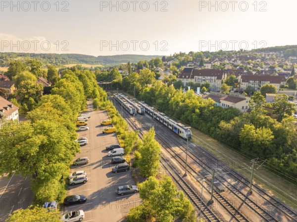 Train and cars in a green environment next to a housing estate, bright summer atmosphere, Weil der Stadt railway station, Böblingen district, Germany