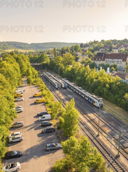 A train runs through a green landscape with trees and a car park, summer atmosphere, Weil der Stadt station, Böblingen district, Germany