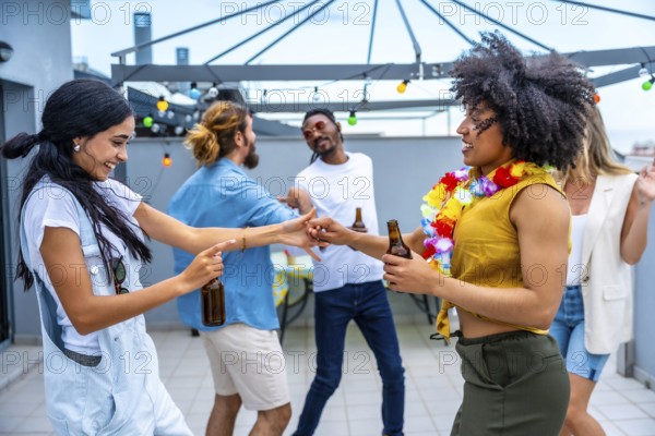 Cheerful young people enjoying drinks and dancing joyfully at a vibrant rooftop party, celebrating summer nights filled with laughter and friendship