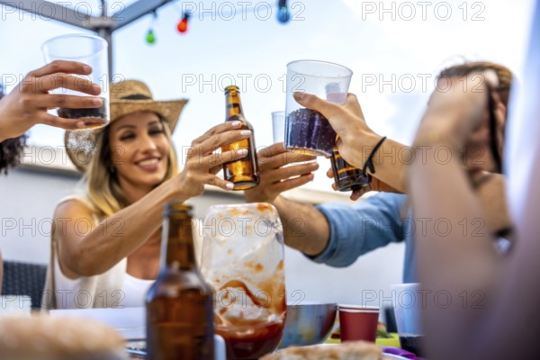 Cheerful friends raising glasses and bottles, making a toast during a rooftop party, celebrating their friendship with joy and excitement
