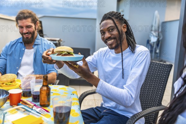 Cheerful friends enjoying a rooftop barbecue party, sharing burgers, drinks, and laughter on a sunny day