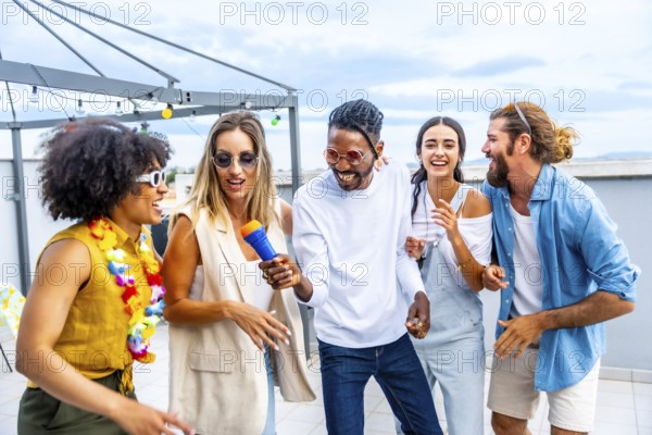 Diverse group of friends enjoying a lively karaoke session, singing, dancing, and celebrating together at a vibrant rooftop party