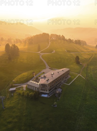 Large building on a hill at sunset in a peaceful mountain landscape, Alpe di Siusi, Dolomites, South Tyrol, Italy