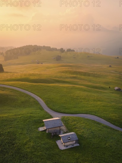 Houses and streets in a hilly landscape in warm evening light, Alpe di Siusi, Dolomites, South Tyrol, Italy