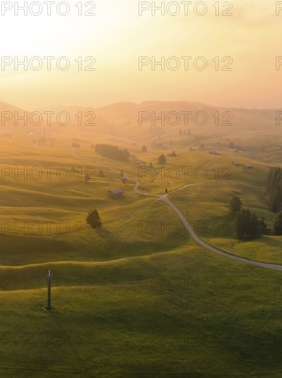 Hilly landscape at sunset with winding paths and warm light, Alpe di Siusi, Dolomites, South Tyrol, Italy