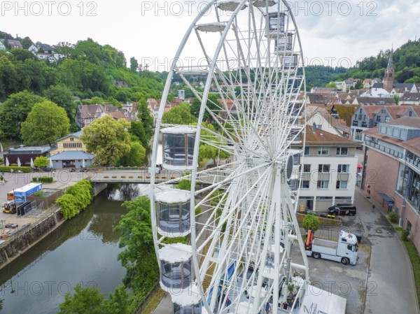 Large Ferris wheel in front of urban background with river in the foreground and green surroundings, construction Ferris wheel, Calw, Black Forest, Germany