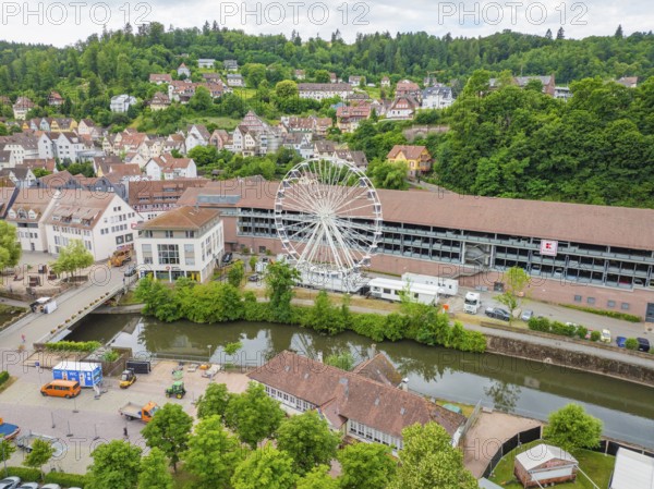 Ferris wheel next to a river and buildings in a green village, Ferris wheel construction, Calw, Black Forest, Germany