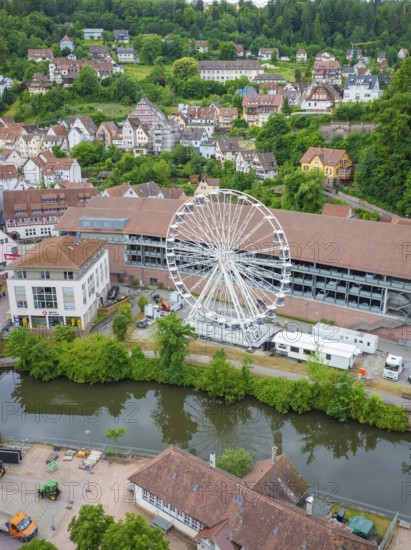 A large Ferris wheel stands in an urban environment near a river and surrounded by residential buildings, Ferris wheel construction, Calw, Black Forest, Germany