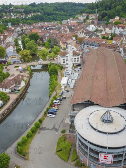 Large building with Ferris wheel by the river in a green hilly village, Ferris wheel construction, Calw, Black Forest, Germany