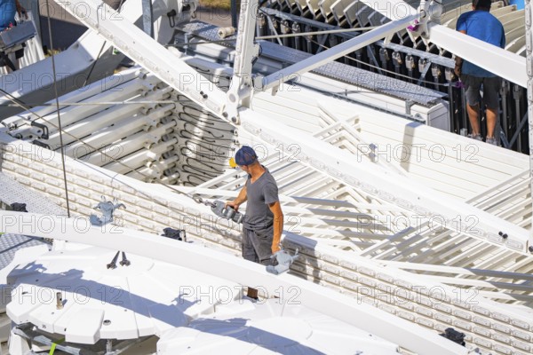 Person standing between technical structures while a Ferris wheel is being erected, Ferris wheel construction for the 950th anniversary of the town of Calw, Black Forest, Germany