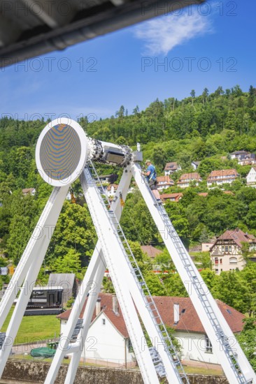 A worker on a Ferris wheel scaffolding with a view of green hills and buildings, Ferris wheel construction for the 950th anniversary of the town of Calw, Black Forest, Germany