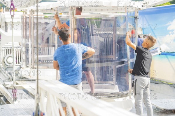 People working on a glass cabin of a Ferris wheel in an amusement park, Ferris wheel construction for the 950th anniversary of the town of Calw, Black Forest, Germany