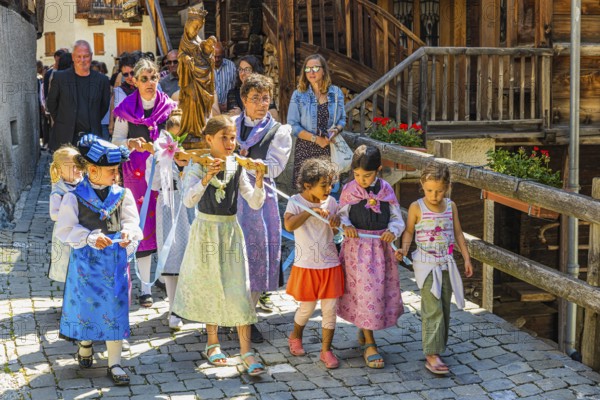 Women and children carrying the statue of the Virgin Mary with the Infant Jesus in the Corpus Christi procession, historic town centre, Grimentz, Val d'Anniviers, Valais Alps, Canton Valais, Switzerland