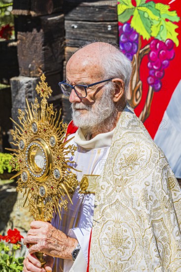 The priest with the golden monstrance during the Corpus Christi procession, historic village centre, Grimentz, Val d'Anniviers, Valais Alps, Canton Valais, Switzerland