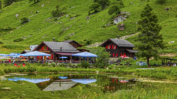 Huts and parasols reflected in the pond, Relais Tzoucdana, Zinal, Val d'Anniviers, Valais Alps, Canton Valais, Switzerland