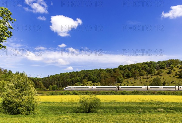 InterCityExpress ICE en route on the Swabian Alb near Lonsee. Landscape on the railway's Filstalline line in spring with rape fields in bloom. Lonsee, Baden-Württemberg, Germany