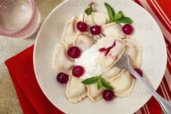 Traditional dumplings with cherries and yogurt, close-up, no people