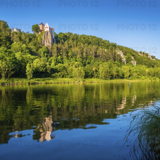 Prunn Castle on a steep cliff above the Altmühl Valley in the evening light, reflection in the river Altmühl as part of the Main-Danube Canal, near Riedenburg, Altmühl Valley nature park Park, Lower Bavaria, Germany