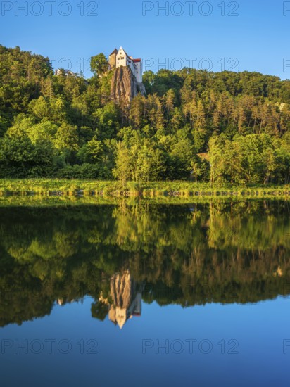 Prunn Castle on a steep cliff above the Altmühl Valley in the evening light, reflection in the river Altmühl as part of the Main-Danube Canal, near Riedenburg, Altmühl Valley nature park Park, Lower Bavaria, Germany