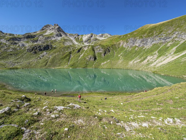Hiker at lake Engeratsgundsee, mountain range between Oberstdorf and Bad Hindelang, Allgaeu, Bavaria, Germany