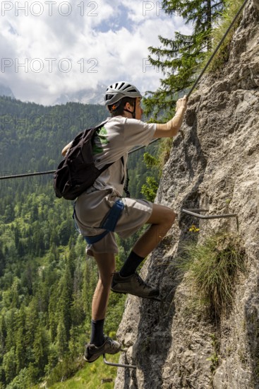 Mountaineer climbing over a steep ladder in the Isidor via ferrata, Grünstein, Schönau am Königssee, Berchtesgadener Land, Upper Bavaria, Bavaria, Germany