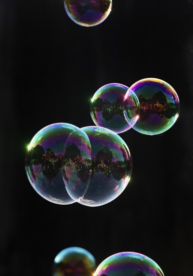 Iridescent soap bubbles in the colours of the rainbow against a black background, Recklinghausen, North Rhine-Westphalia, Germany