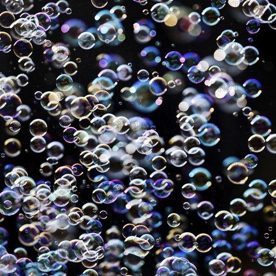 Many, small iridescent and floating soap bubbles against a black background, Recklinghausen, North Rhine-Westphalia, Germany
