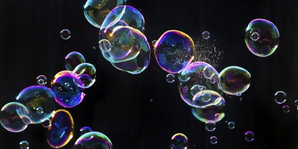 Iridescent soap bubbles with a just burst bubble in front of a black background, Recklinghausen, North Rhine-Westphalia, Germany