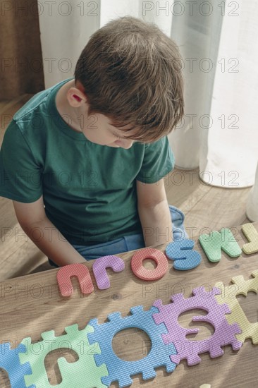 Boy with autism, expresses frustration, playing with puzzle pieces, on a wooden table, natural light, lifestyle