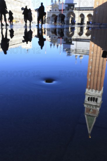 Reflection of the Campanile with water vortex of the flowing flood water, Acqua alta, Venice, Veneto, Italy