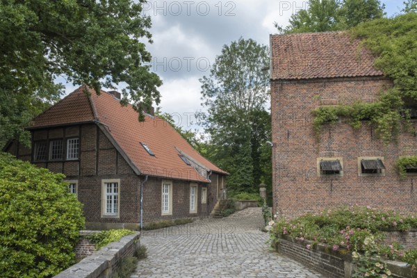Idyllic rural scene with a half-timbered house and brick building under a cloudy sky, Haus Welbergen, Welbergen, Ochtrup, Münsterland, North Rhine-Westphalia, Germany