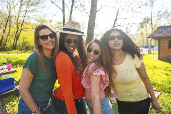 Four multi ethnic female friends are having a picnic in a park, enjoying the sunny weather and each other's company