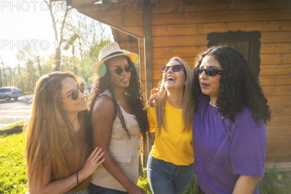 Four diverse female friends laughing and bonding under the warm sun, enjoying a carefree day outdoors in a vibrant park setting