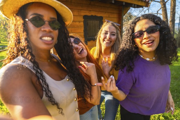 Four friends enjoying a sunny day in the countryside, capturing joyful moments together while taking a fun selfie during their vacation