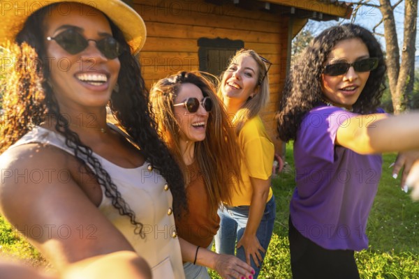 Four multi ethnic female friends are laughing and taking a selfie on a sunny day, enjoying their time together