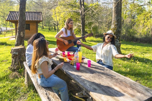 Four young women enjoying a sunny day at the park, playing music, eating fruit, and having fun together