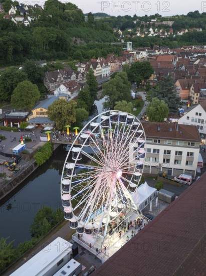 Ferris wheel in an evening city scene next to a river, 950 years of Calw, Germany