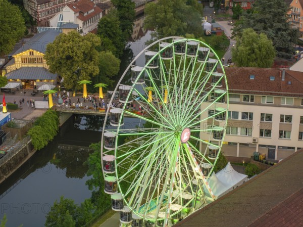A green Ferris wheel stands near a bridge and a river, surrounded by trees, 950 years Calw, Germany