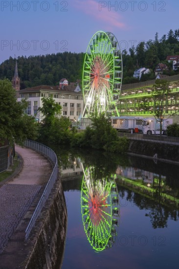 Close-up of a green illuminated Ferris wheel in front of an evening sky with pink clouds, 950 years Calw, Germany