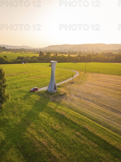 Observation tower with a winding path and hilly landscape at sunset