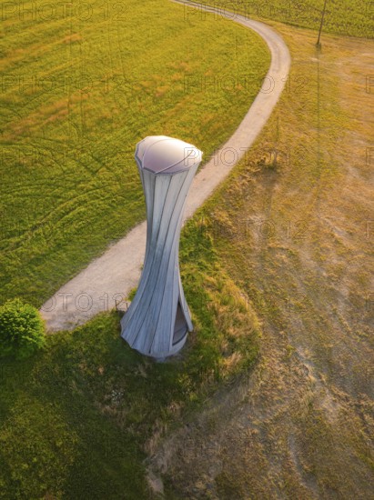 Modern tower on a field with a curved path in the evening light