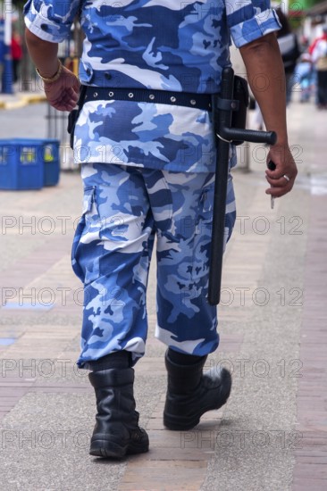 Policeman walking in the street, From behind, City of Quito. Pichincha province, Ecuador, South America