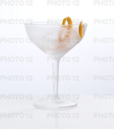 Frosted empty cocktail glass with orange zest as garnish against a white background, studio shot