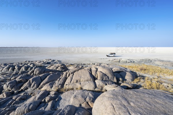Round rocks of Kubu Island with view over the salt pan, off-road vehicle on the salt pan, Kubu Island (Lekubu), Sowa Pan, Makgadikgadi Salt Pans, Botswana