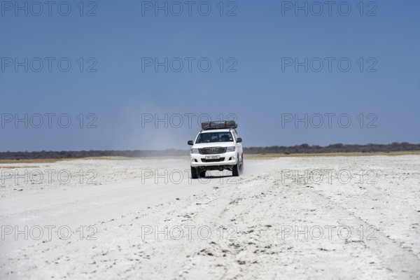 Off-road vehicle driving on a wide empty salt pan, Makgadikgadi Salt Pans, Botswana