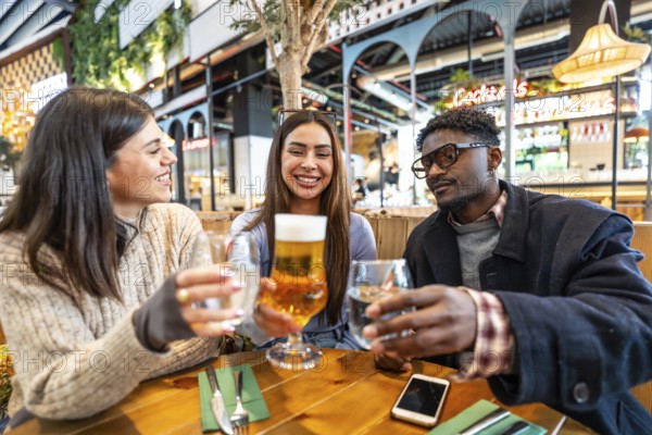 Happy multi ethnic friends toasting drinks at a brewery, enjoying each other's company and celebrating friendship in a lively atmosphere