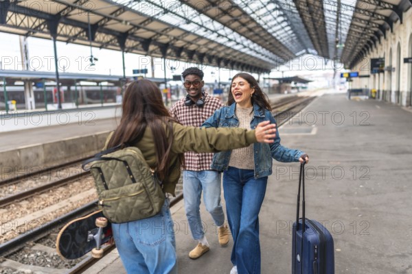 Happy multi ethnic friends meeting at train station, hugging each other, and starting their vacation together