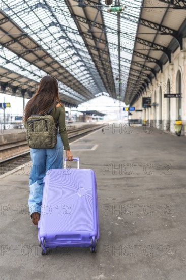Tourist walking along a train platform, pulling a trolley suitcase while embarking on an exciting travel adventure